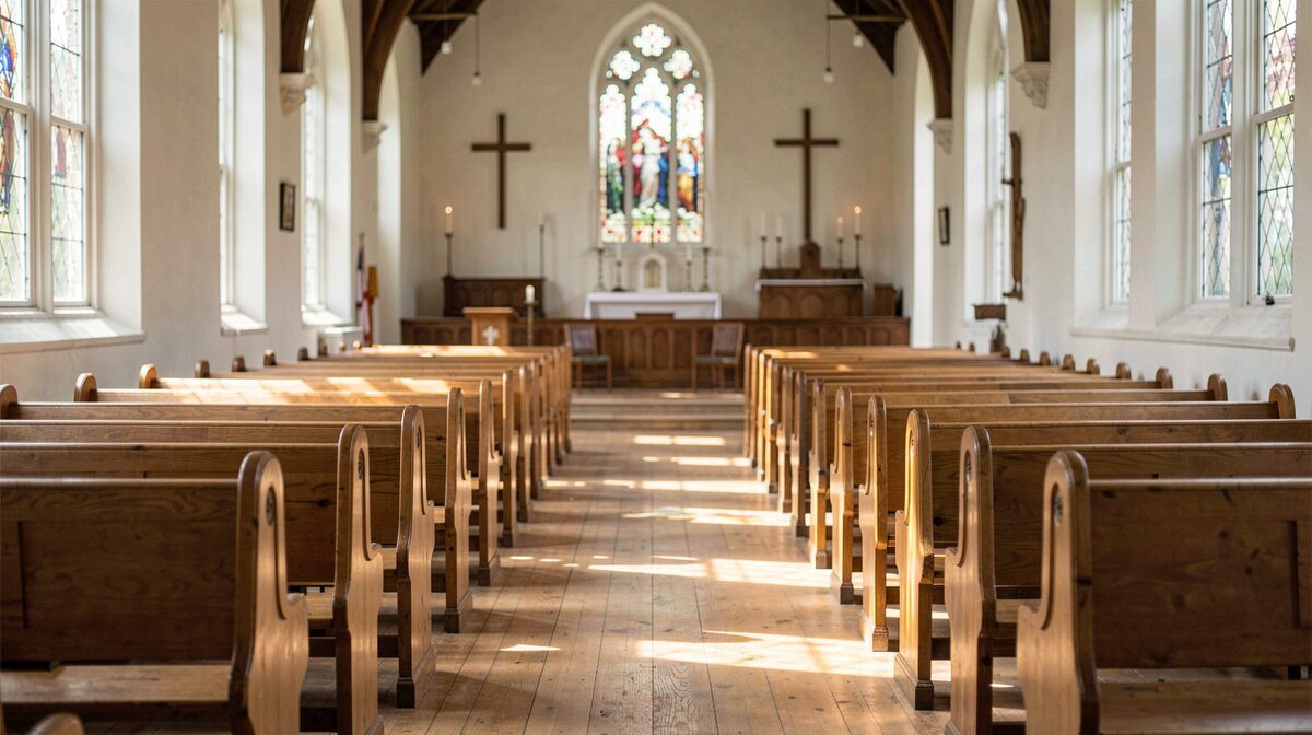 Een lege kerkzaal op een doordeweekse ochtend, zachte zonnestralen door hoge ramen op houten banken, gefotografeerd vanaf het middenpad.